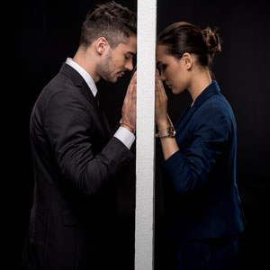 A tense moment captured as a man and woman lock eyes through a doorway, reflecting the troubled state of their relationship.