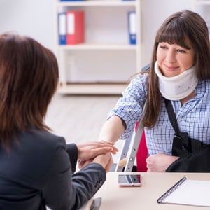 A woman with a neck brace and another woman shaking hands, possibly in a medical or supportive context.