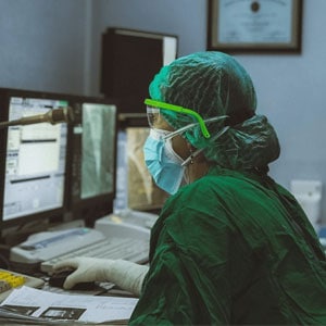 Operating room scene with surgeon in green scrub suit working on computer.