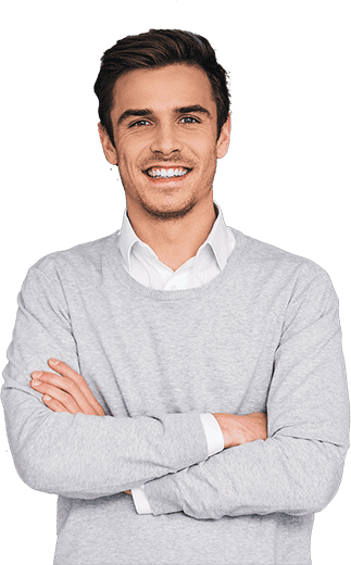 A man in a grey sweater standing with his arms crossed.