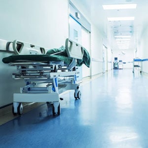 A hospital bed in a hallway with a blue floor.