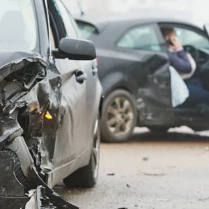 A damaged car after an accident, showing dented bodywork and a cracked windshield.