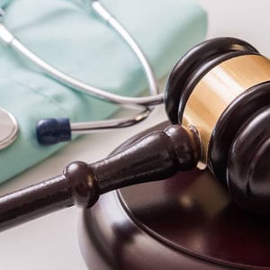 A gavel and stethoscope on a table with a medical file