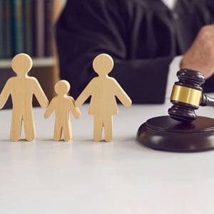 A wooden family, gavel and a judge symbolize the concept of family law.