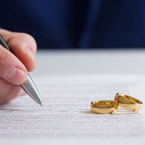 A family law attorney is signing the papers while the rings are on the paper.