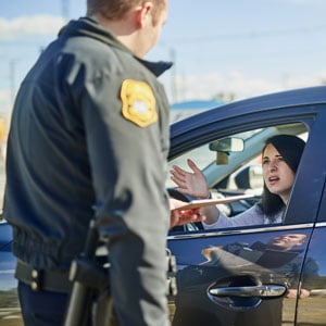 A police officer inquiring a woman about a possible DUI while she sits in her car.